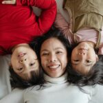 photo of woman and her children lying on bed